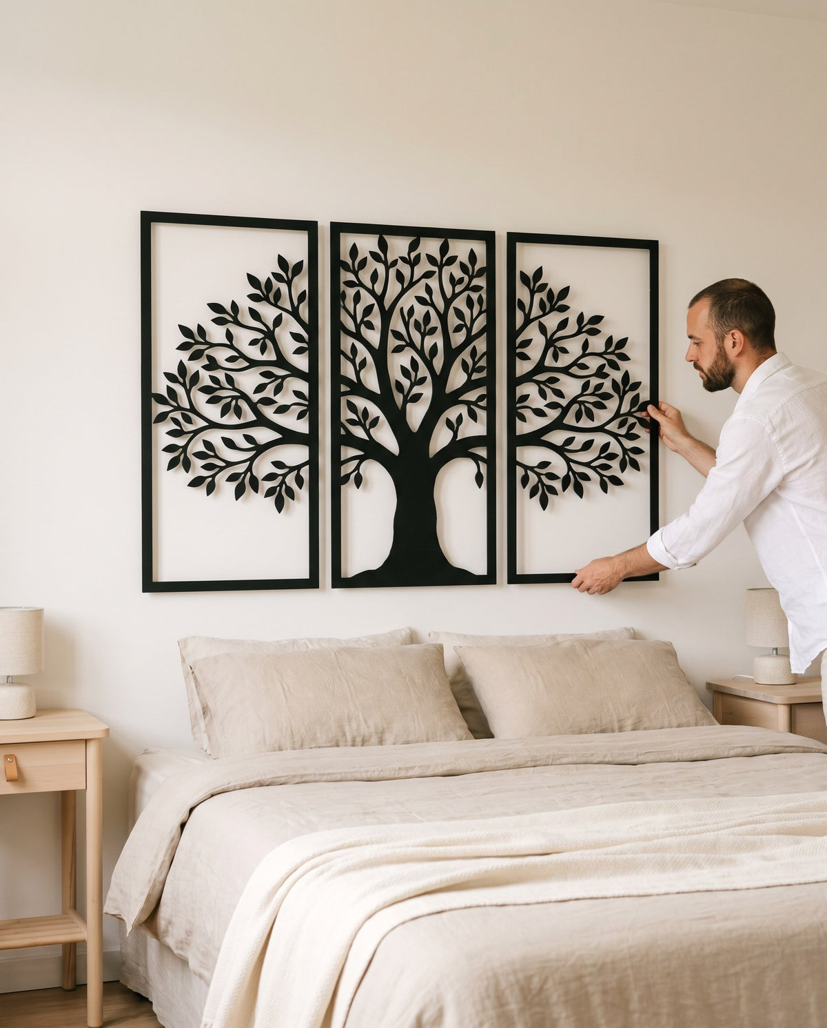 Triptyque arbre de vie en métal noir au-dessus d'un lit de 160, un homme ajuste le panneau de droite