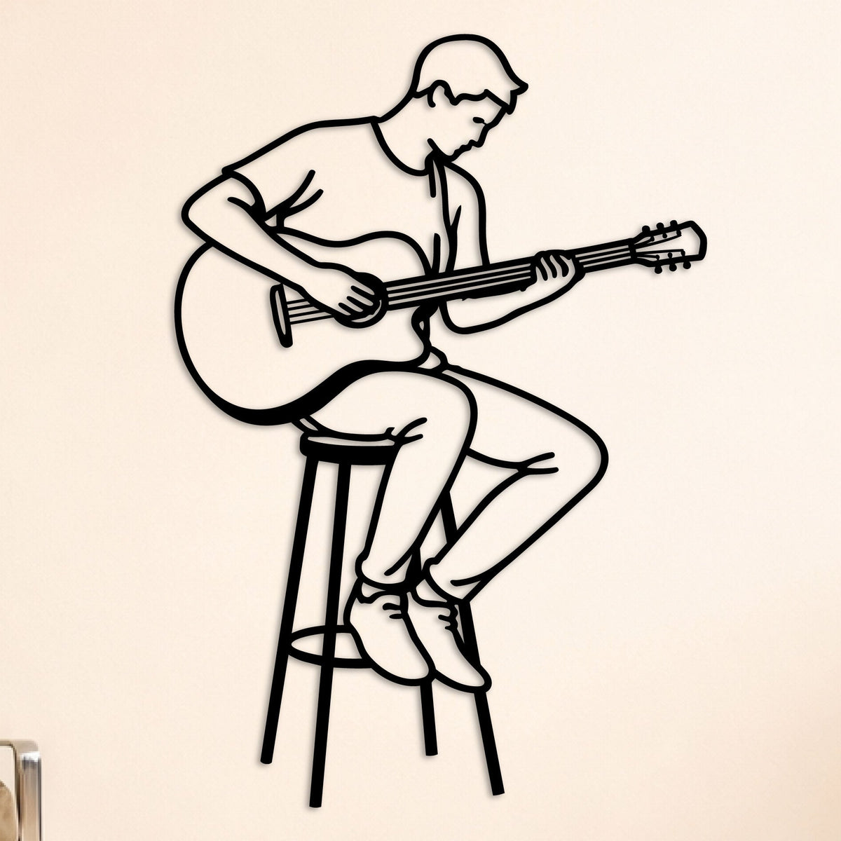 Guitariste assis sur un tabouret, déco murale en métal noir